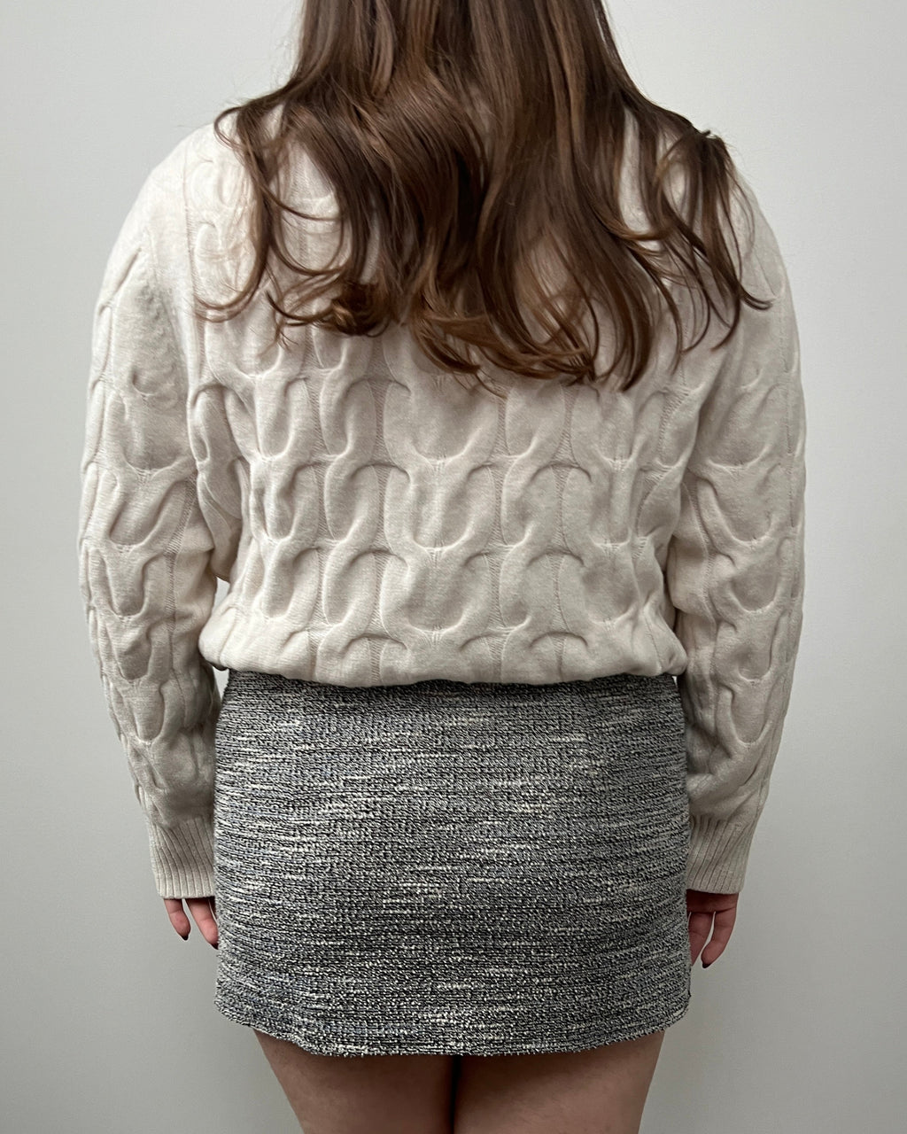 A female wearing a tweed gray mini skirt.