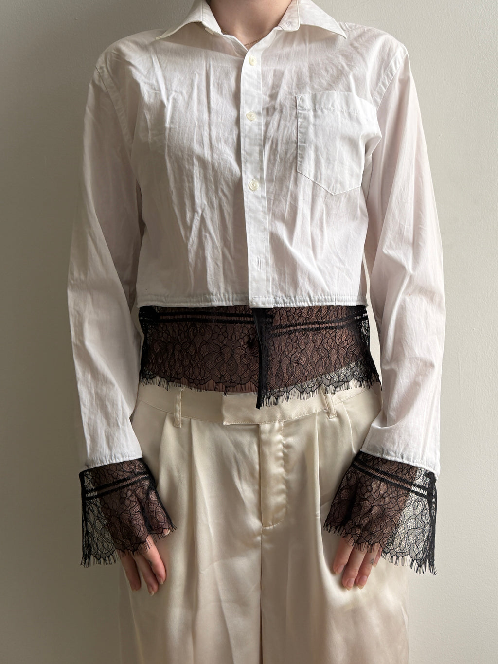 White shirt with black lace cuffs and hem on a neutral background
