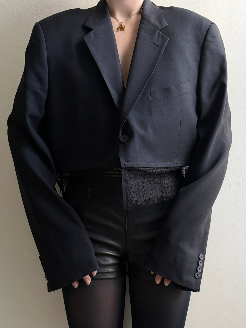 Person wearing a dark lace trim blazer with a white background