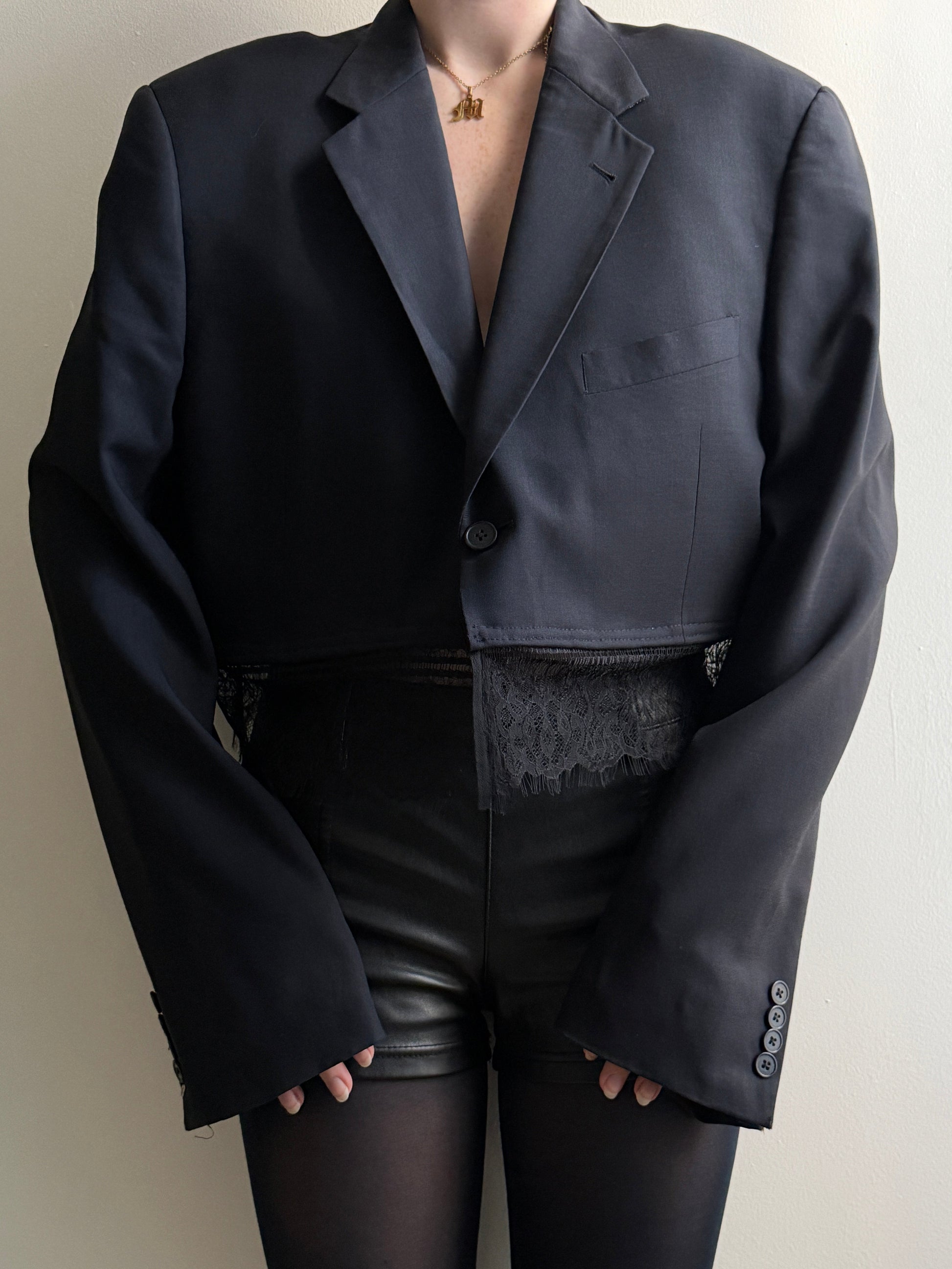 Person wearing a dark lace trim blazer with a white background