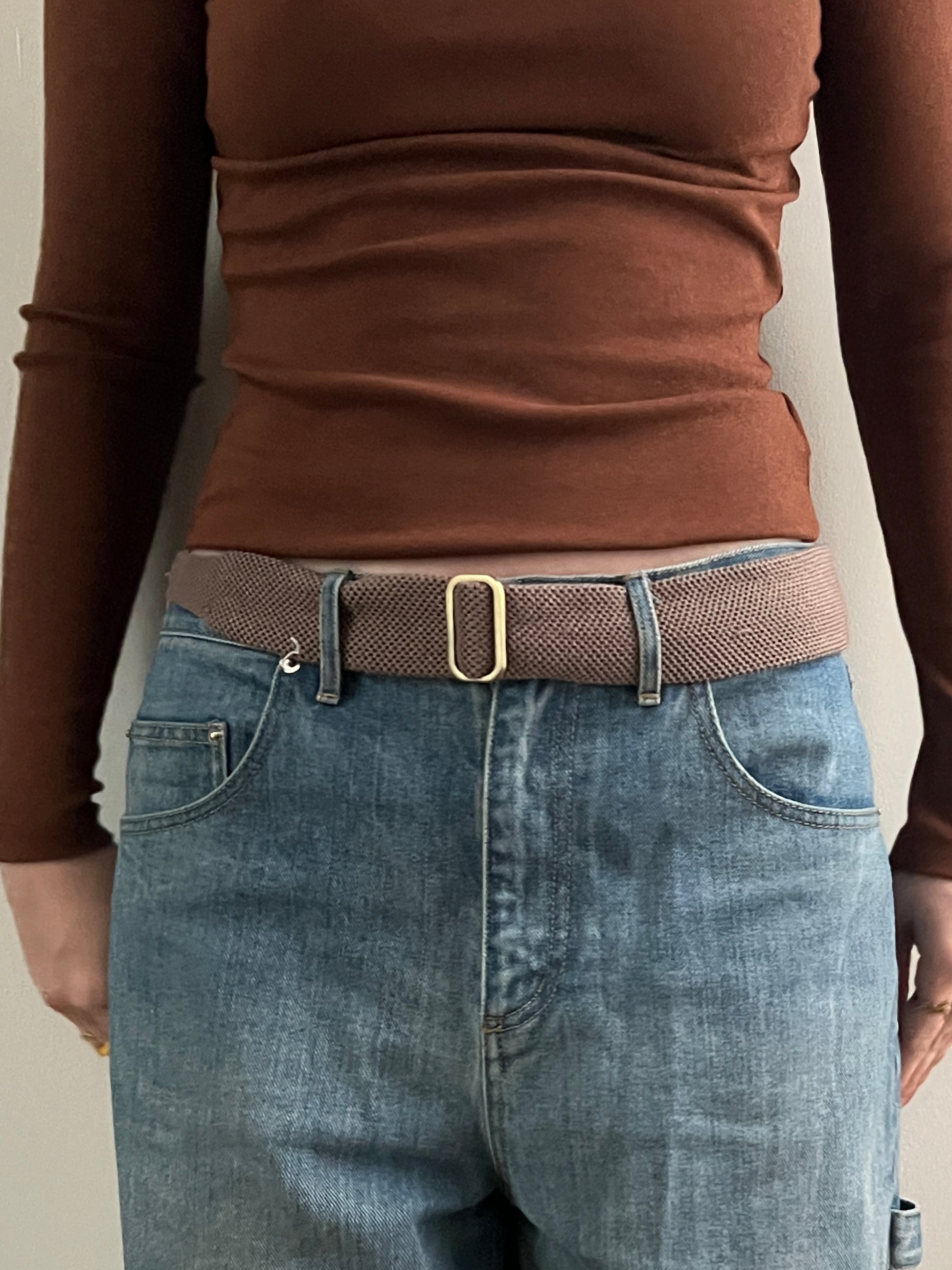 Person wearing belt on beige background
