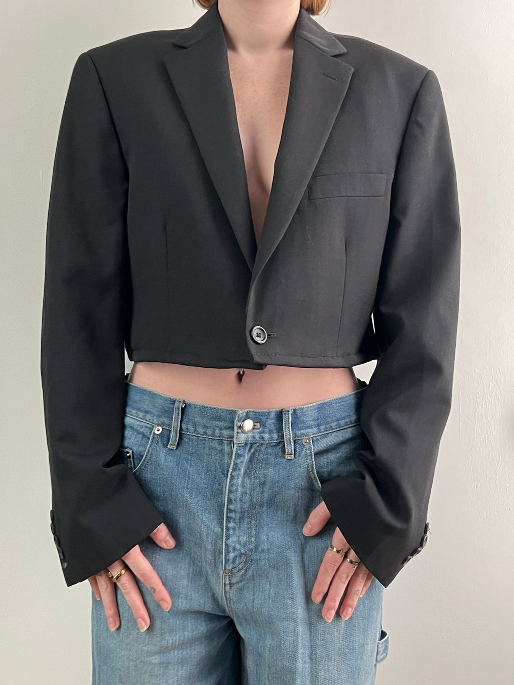 Female wearing a cropped black blazer on a plain background