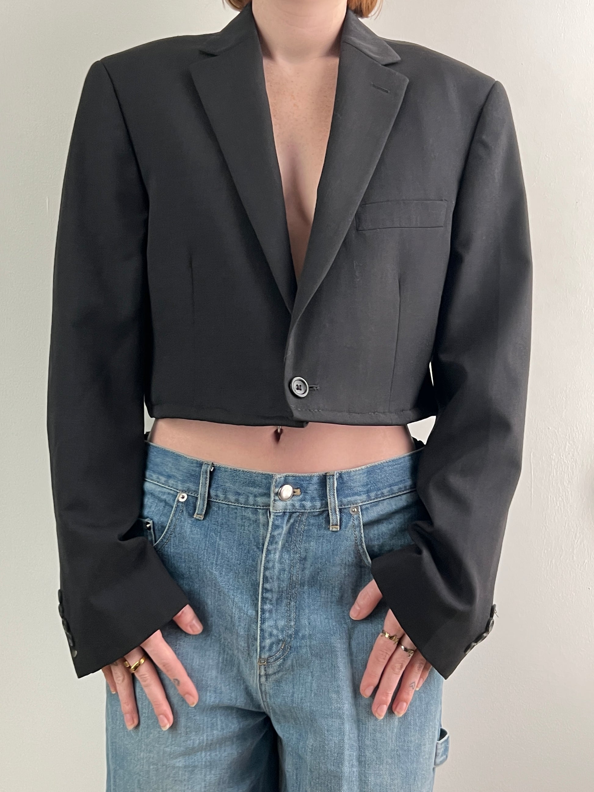 Female wearing a cropped black blazer on a plain background