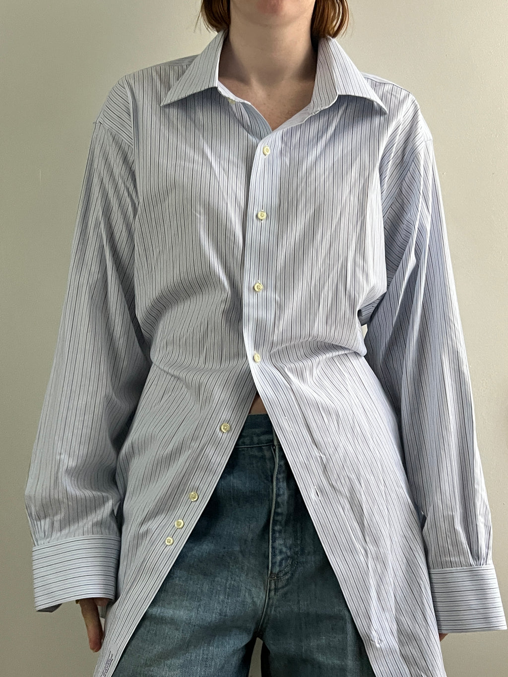 Female wearing a blue and gray striped blouse with a cinched back facing front.