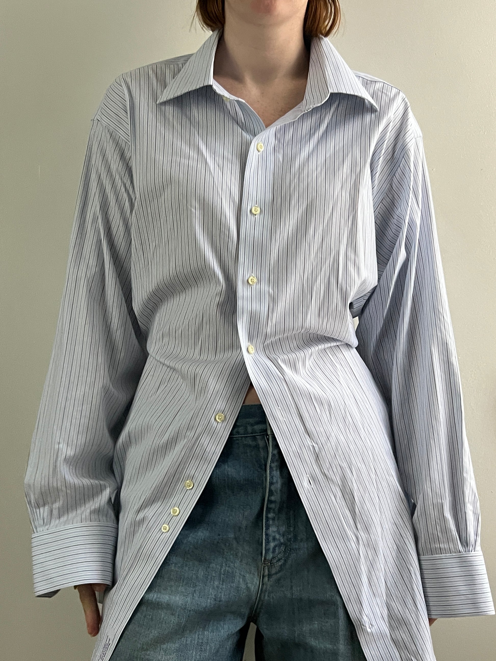 Female wearing a blue and gray striped blouse with a cinched back facing front.