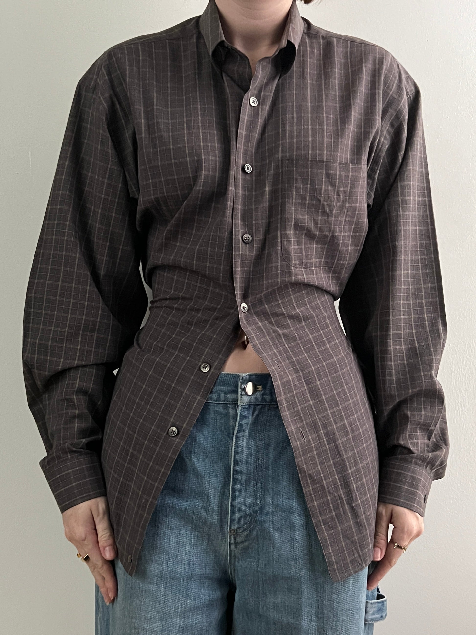 Female wearing a brown checkered long sleeve button down blouse with a neutral background