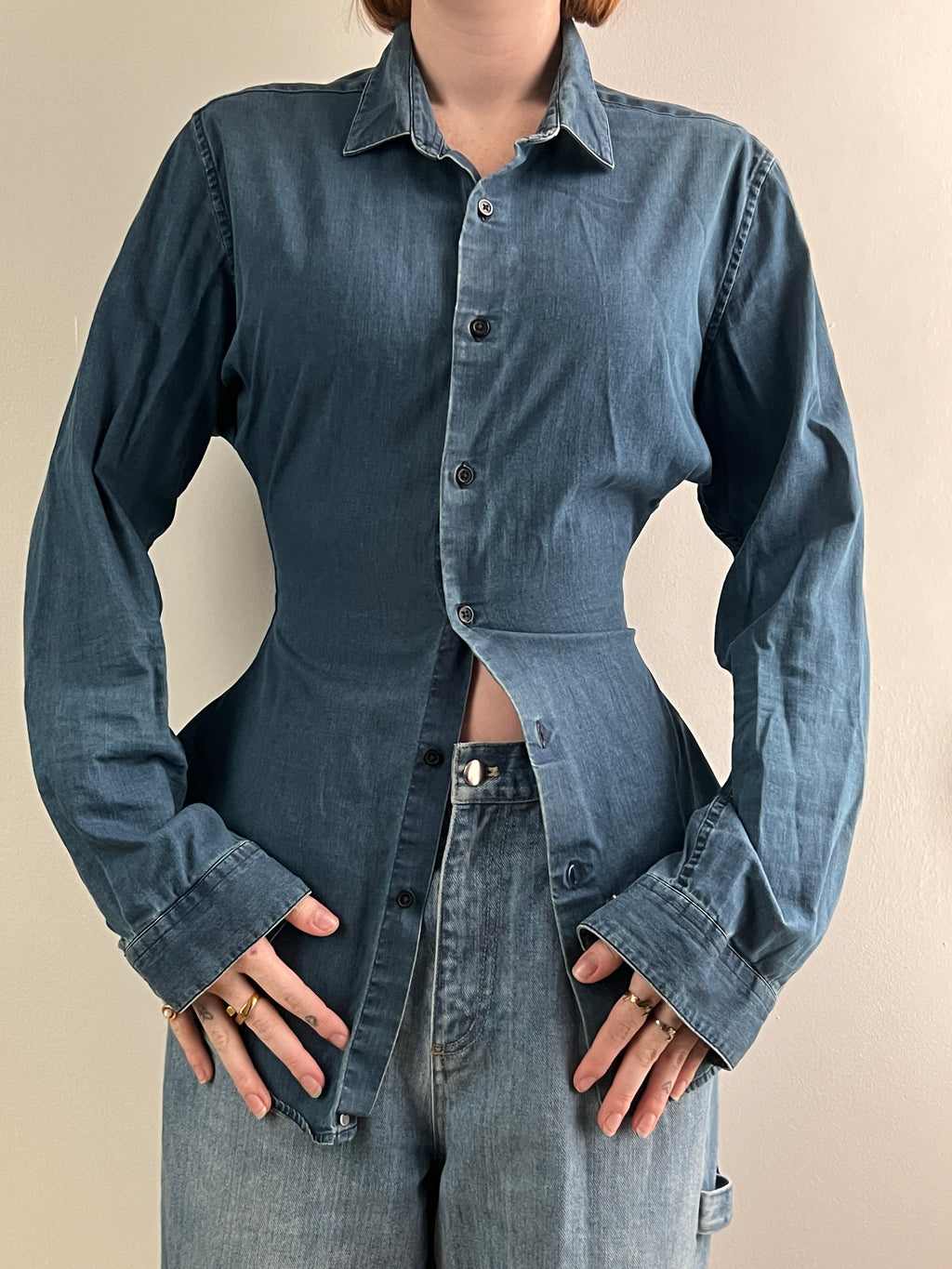 Female wearing a medium dark denim button down blouse with a cinched elastic back facing front.