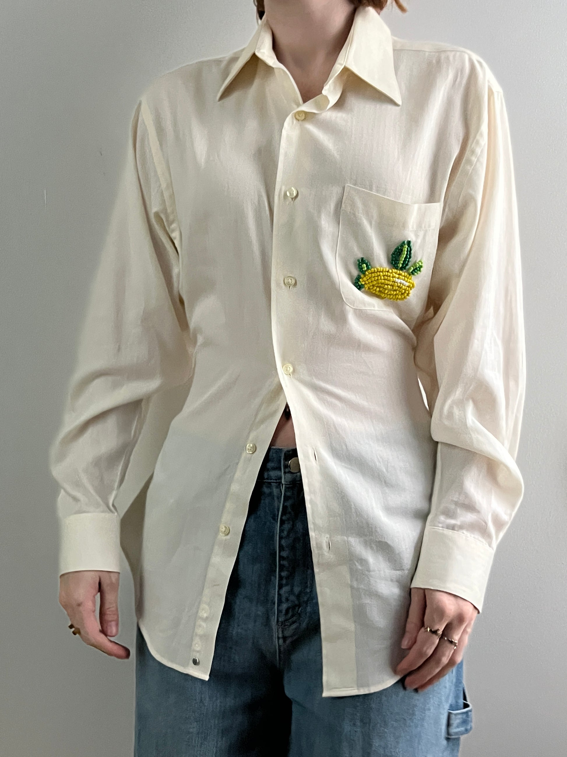 Female wearing a pale yellow button down blouse with a cinched elastic back facing front.