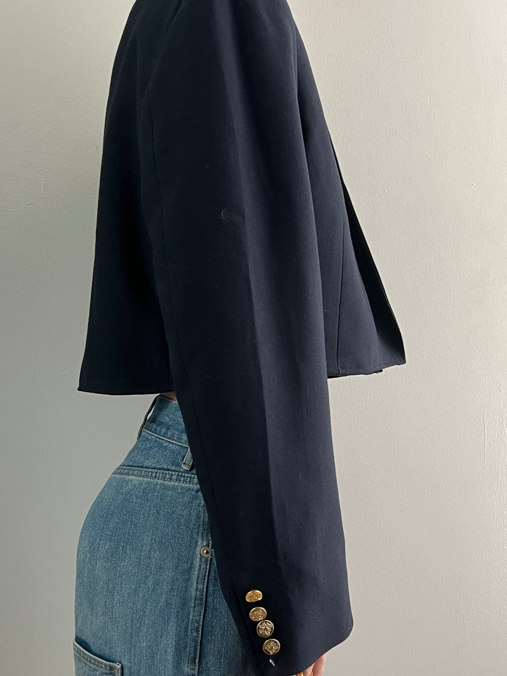 Navy blazer with gold buttons on a plain background